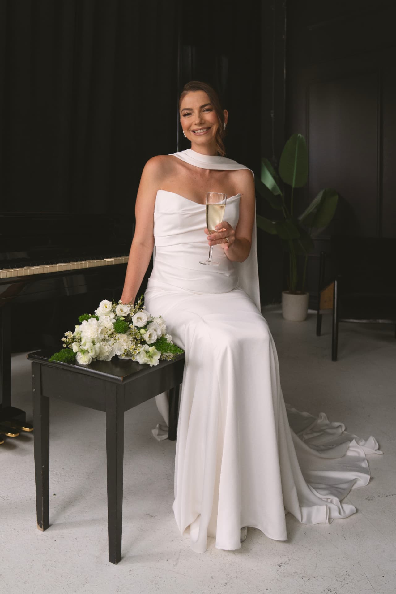 La mariée avec une coupe de champagne près du piano