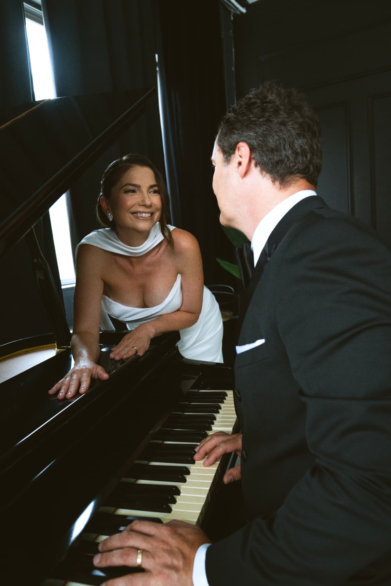 Le couple se souriant autour du piano à queue