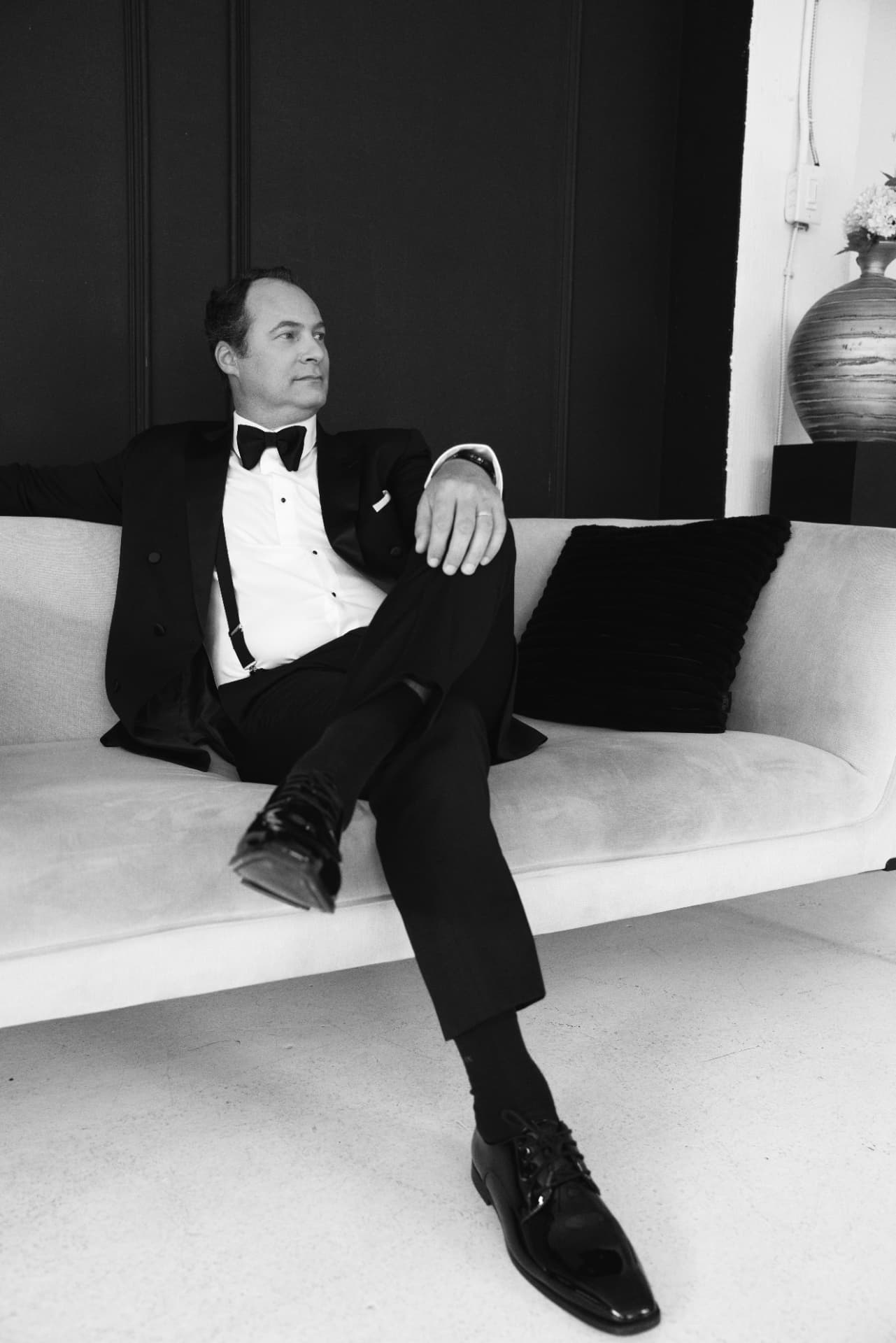 Portrait du marié en smoking et bretelles sur le divan